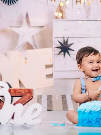 The pure joy of a first birthday cake smash! This little boy, dressed in a smart blue bow tie, can't hide his excitement in our fully-equipped studio, set for a fun and messy celebration.