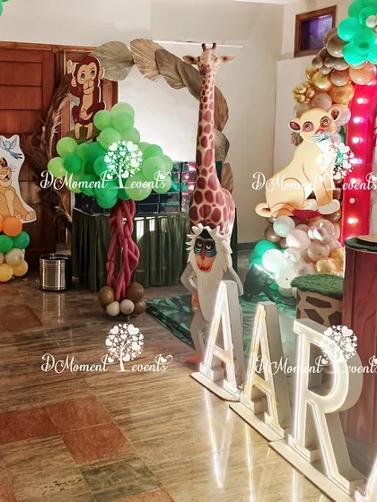 A corner of the Lion King party, showing marquee letters, a tall giraffe prop, and other character cutouts that help build the immersive jungle atmosphere.