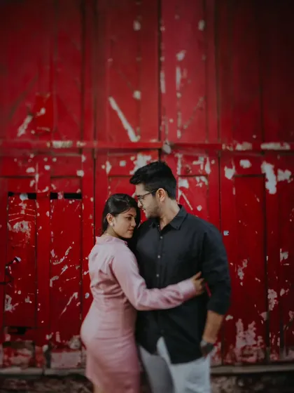 A close-up, intimate portrait of a couple against a vibrant, textured red wall, creating a bold and passionate image during their Mumbai street photoshoot.
