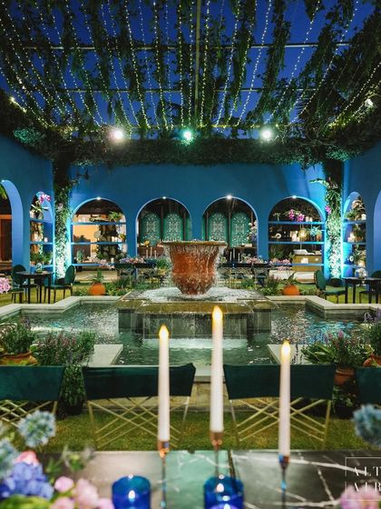 The pre-cocktail area for 'Midnight Mirage', transformed into an enchanting alfresco patio. The space featured a central fountain, graceful arches, and a ceiling of lush greenery and fairy lights.