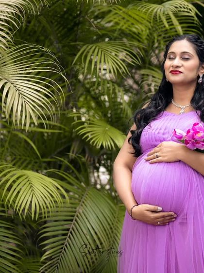 The beauty of nature complementing the beauty of motherhood. A serene outdoor maternity portrait with the mom-to-be in a lovely purple gown, surrounded by lush green palms.