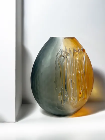 A striking blend of smoky grey melting into warm amber, this blown glass vase is a true conversation starter. Its organic oval form and textured finish make it a modern art piece for your home.