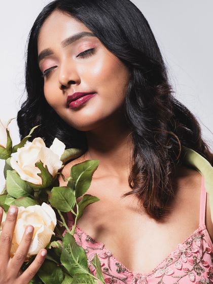 A serene beauty shot with the model's eyes closed, smelling the roses.