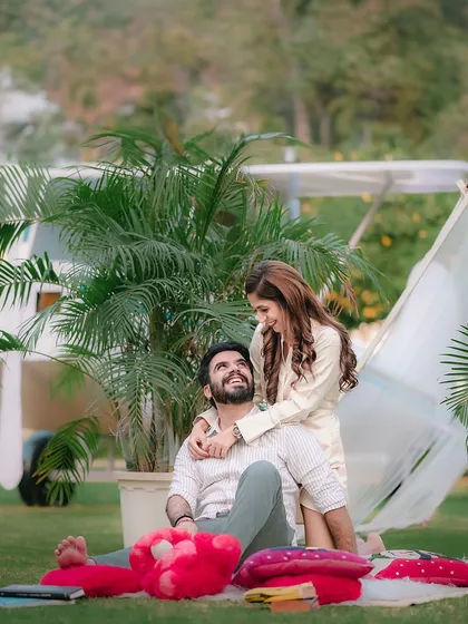 A playful interaction between a couple during their picnic-themed shoot, showcasing their natural chemistry. The setting includes our vintage bicycle and airplane for a whimsical touch.
