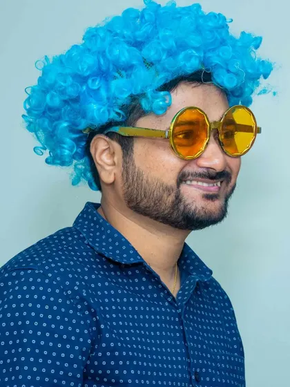 An adult guest enjoying the party with a bright blue curly wig and round yellow glasses. My prop collection has something fun for every age.