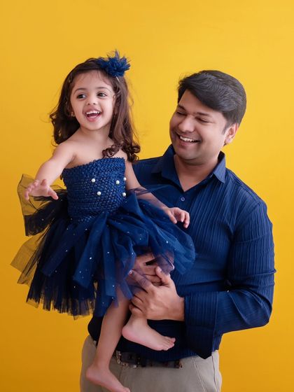 A father's joy is contagious. This candid shot captures a beautiful, happy moment between a dad and his daughter against a vibrant yellow background, full of laughter and life.