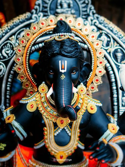 A full, straight-on view of the majestic black Ganpati idol, adorned with golden jewelry. This photo captures the complete, powerful presence of the deity.