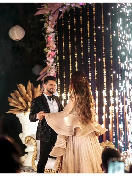 The couple shares a dance under a curtain of fairy lights, creating a magical and romantic atmosphere.