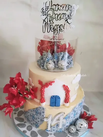Your story can be a destination. This Greece-inspired cake was designed for a teenager's dance party, featuring iconic blue and white patterns, bougainvillea, and even tiny disco balls to get the party started.