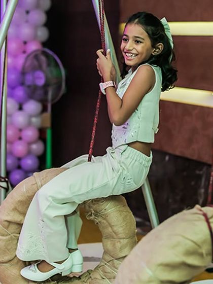 A happy girl enjoying a tire swing, part of our custom-built indoor obstacle course. It's all about creating unique and playful experiences.