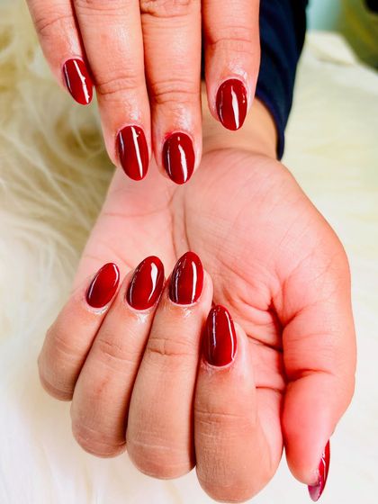 A perfect, classic red manicure. These almond-shaped nails are coated in a rich, vibrant red gel polish with a high-gloss finish.
