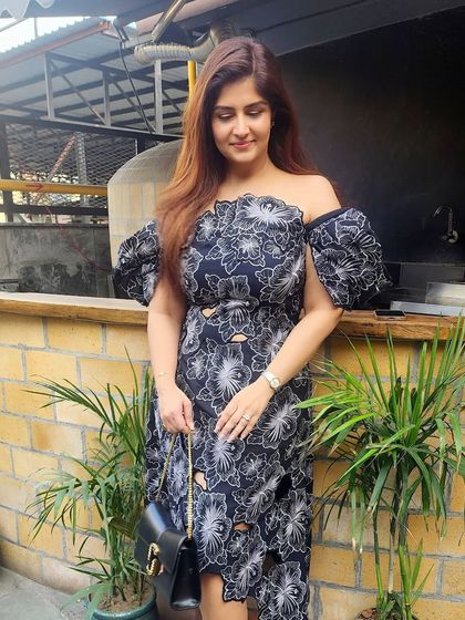 A beautiful off-shoulder black dress with white floral embroidery and an asymmetrical hemline, perfect for a cocktail party or evening event.