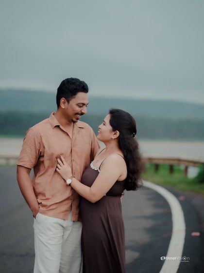 The couple shares an intimate moment on a scenic road. The natural, moody lighting and the beautiful landscape create a perfectly romantic atmosphere.