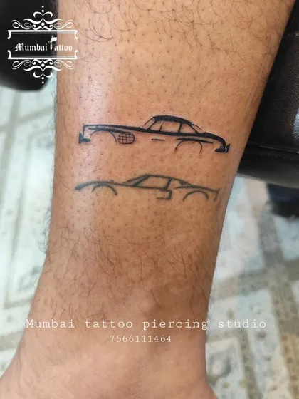 A minimalist line art tattoo of two classic Mercedes cars. This is a sleek and stylish design for any car enthusiast, showing that even bold interests can be represented with fine lines.
