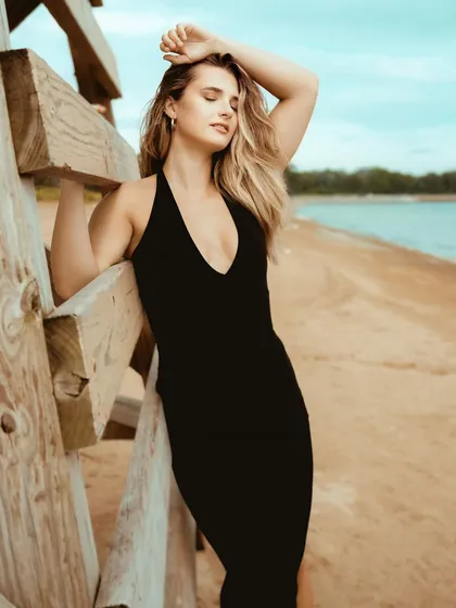 A powerful and sensual pose on the beach, with the model's eyes closed, soaking in the sun and the sea breeze.