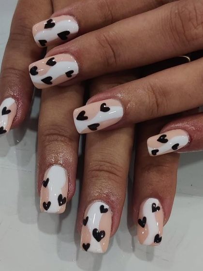 A stylish and unconventional heart design, featuring black hearts on a color-blocked background of nude and white. This is a more graphic, edgy take on heart nail art.