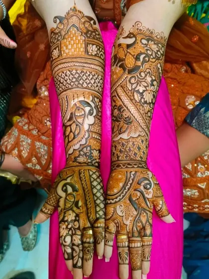 A classic bridal design with a heavy focus on peacock motifs. The birds are rendered in different styles, from the palms to the arms, creating a cohesive and elegant theme.