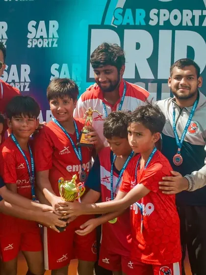 A team shares a special moment with their coaches, celebrating their hard-earned trophy.