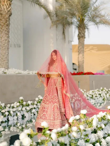 A bride's walk down an aisle of dreams. I styled this moment with a mirrored walkway lined with white flowers, reflecting her stunning pink Falguni Shane Peacock lehenga and the open sky of Abu Dhabi.