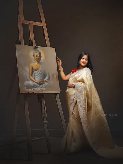 A unique concept blending art with motherhood. The mother-to-be, dressed in a beautiful saree, is posed as if painting a serene image of Buddha, symbolizing peace and creation.