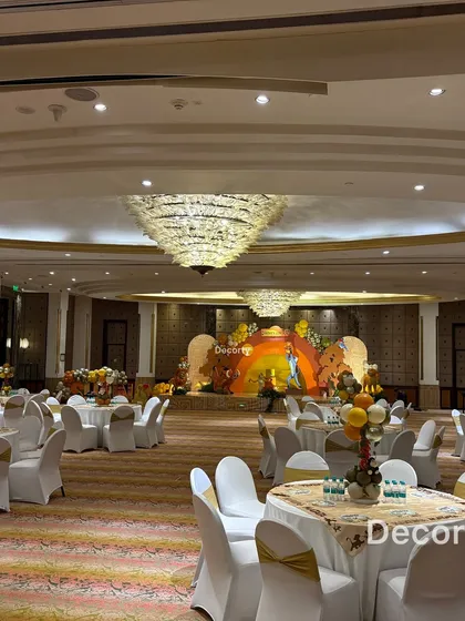 A wide-angle view of the entire banquet hall decorated for the Lion King birthday, showing the stage, guest tables, and grand chandeliers.