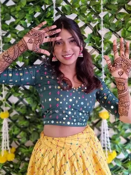 A joyful client showing off her festive mehndi, perfect for a sangeet or wedding party.