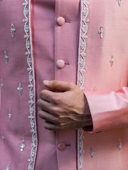 A close-up on the delicate hand-embroidery and button details of the pink Indo-Western jacket, showcasing the high level of craftsmanship.