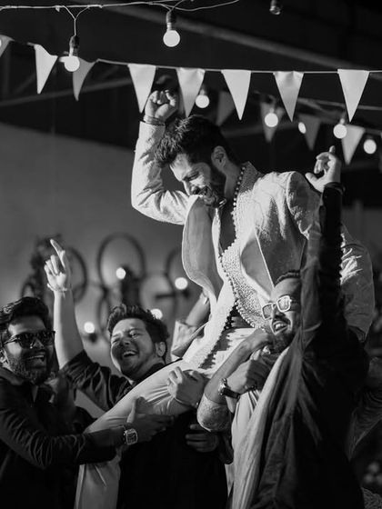 The groom being lifted by his friends on the dance floor, a classic moment of celebration and friendship.