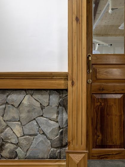 A close-up showing our philosophy of material honesty, where new wooden door frames meet the original stone walls of the building, celebrating the history of the structure.