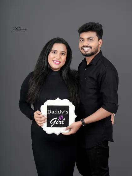 A joyful couple portrait announcing "Daddy's Girl." Their coordinated black outfits and the sweet sign make for a perfect and personal gender reveal announcement.