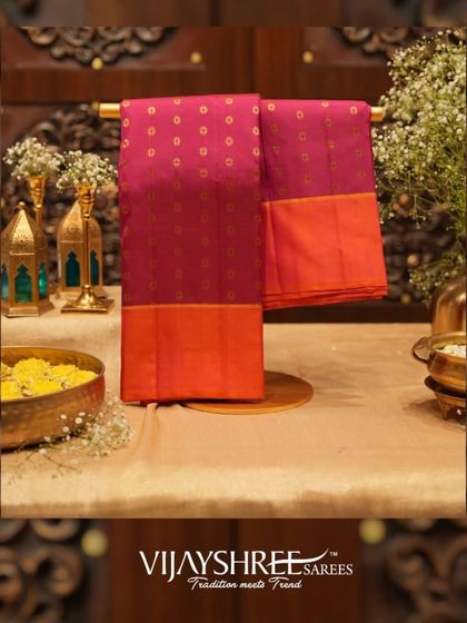 A maroon Kanjivaram with an orange border and gold zari buttas, a classic and royal combination.
