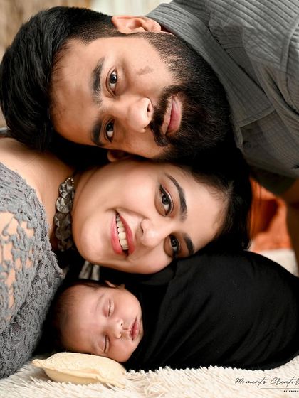 A sweet and cozy family close-up. The parents and their sleeping newborn are nestled together, creating an intimate portrait that is full of warmth and love.
