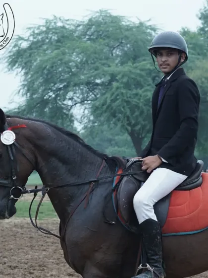 A young man in formal riding attire sits proudly on his horse, ready for a competition or advanced training session.