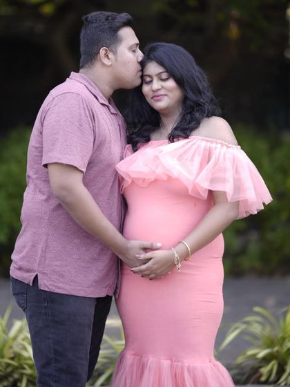 An intimate close-up of a couple during their outdoor maternity shoot. The off-shoulder detail of the pink mermaid gown is featured in this tender moment.