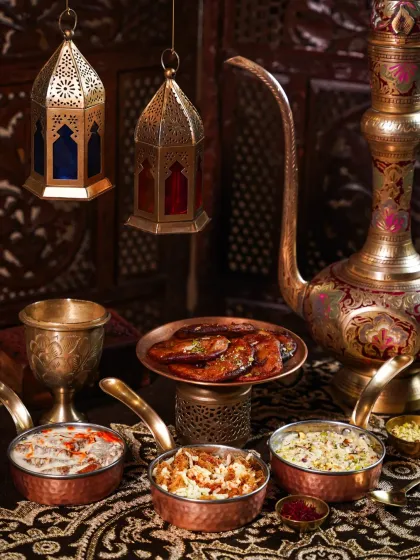 A collection of rich Awadhi desserts like Shahi Tukda and Phirni, set against a backdrop of hanging lanterns. The warm, glowing light creates a festive and opulent atmosphere perfect for an Eid celebration.