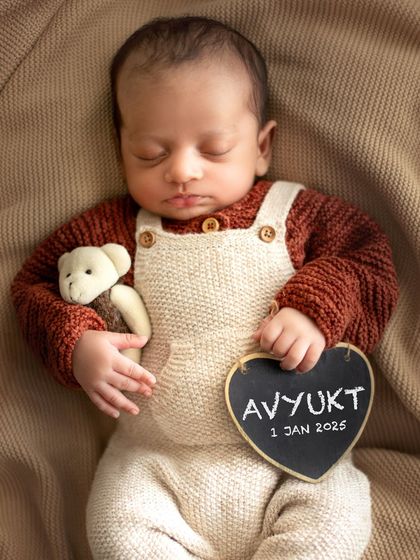 Another personalized portrait, with the baby's name and birthdate on a chalkboard heart. He's dressed in an adorable knit overall set.