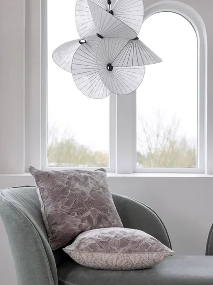 A close-up of the Serpentine Light, showing its delicate, fan-like paper structure against a window, emphasizing its translucency and lightness.