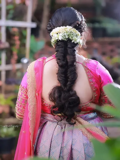 A detailed shot of the back, focusing on the intricate braid and floral hair accessory. This highlights the skill of the hairstylist and the completeness of the bridal look.