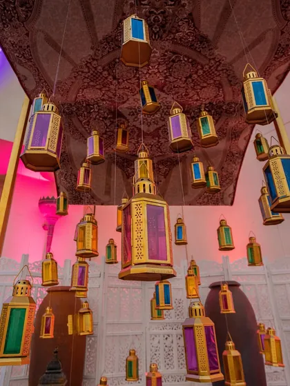 A ceiling installation of colorful Moroccan lanterns, creating a magical, bazaar-like atmosphere for an evening event.