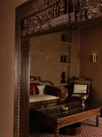 A view into the consultation area, framed by a magnificent, antique carved wooden doorway. This is a dialogue between past and present, craft and couture.