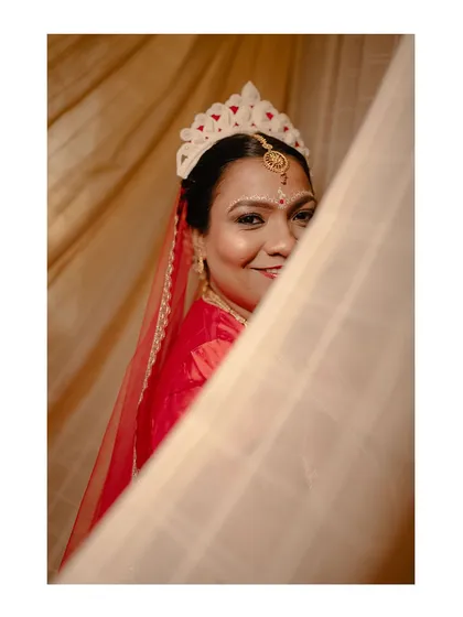 The beautiful Bengali bride, Susheta, with her traditional 'mukut', peeking out from behind a curtain.