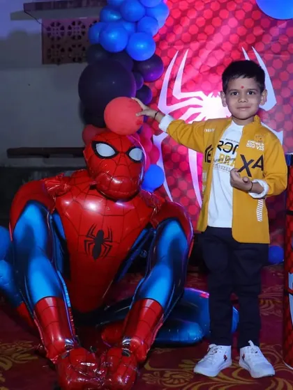 A close up of the birthday boy with a large Spiderman foil balloon. We use a mix of props and balloons to add depth and fun to our themed birthday decorations.