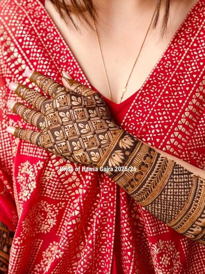 A close-up of a back-of-hand design against the bride's red outfit. The intricate floral and jaali patterns create a beautiful texture that complements her look perfectly.