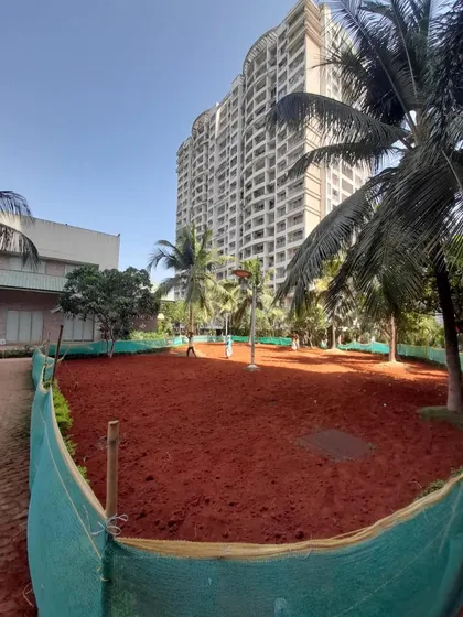A wide view of the prepared site, with the red soil evenly spread and enclosed by a green net to protect the area.
