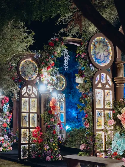 A close-up of the enchanted entrance arch, with its stained-glass effect windows and lush, colorful floral arrangements.