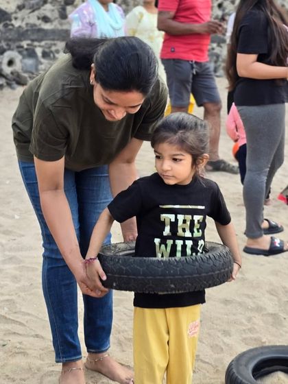 A parent helps her child with a tire-lifting exercise. Our beach playdates are a wonderful opportunity for parents and kids to bond while being active together.