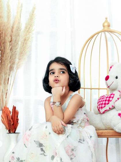 Pondering her next royal decree. This little princess, sitting with her teddy bear, is the picture of innocence and charm.