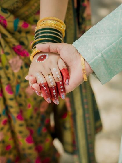 A close-up of the couple holding hands, showcasing the bride's beautifully decorated hands with 'Aalta' and her engagement ring, symbolizing their union.