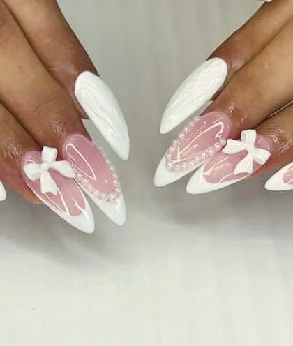 The ultimate in chic and feminine design. These long, stiletto nail extensions feature a clean white finish, delicate pearl hearts, and sculpted 3D bows, perfect for a bridal party or any special occasion.
