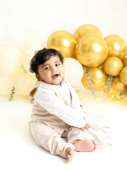 A simple and classic first birthday portrait. The gold balloons add a touch of celebration while keeping the focus on this little one's happy and infectious smile.